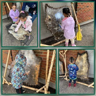 Children stretching and working a hide on a wooden frame outside the school.