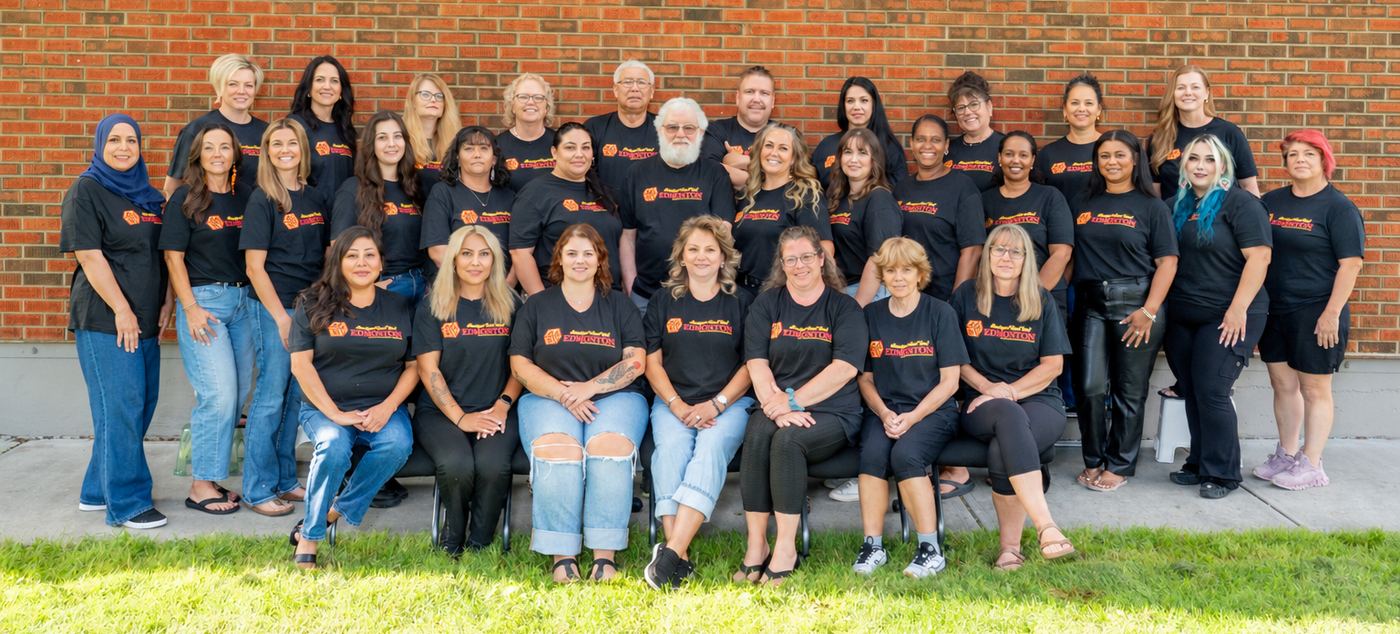 The Aboriginal Head Start Edmonton staff gathered together outside the school in program shirts