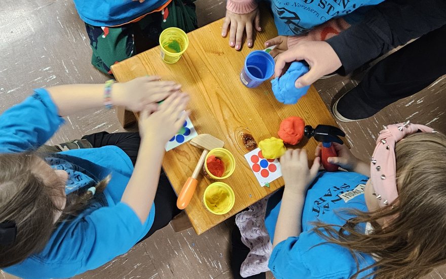 Children around a low wooden table shaping coloured playdough together